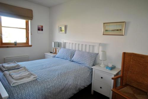 a bedroom with a bed with a blue comforter and a window at Seahaven- family home in East Neuk coastal village in Anstruther