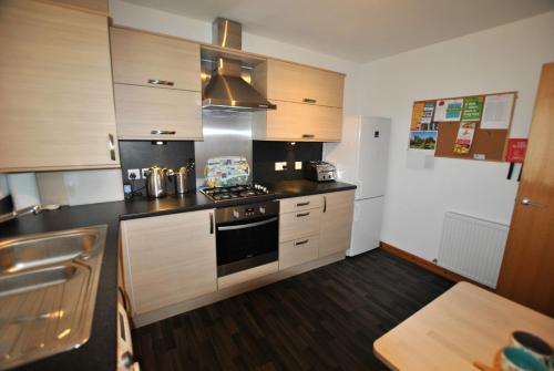 a kitchen with wooden cabinets and a stove top oven at Seahaven- family home in East Neuk coastal village in Anstruther