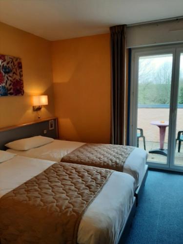 Una habitación de hotel con dos camas y una gran ventana. en Au Relais de l'Oust, en Josselin