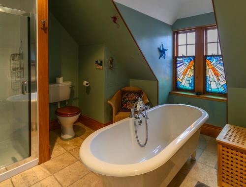 a bathroom with a tub and a toilet and stained glass at Crail Posthouse - 19th Century traditional house in Crail