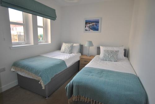 two beds in a room with two windows at The Neuk- contemporary coastal apartment in Anstruther