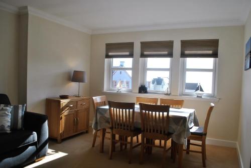 a dining room with a table and chairs and windows at Forth View- stylish upper apartment with sea views in Anstruther