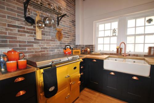 a kitchen with a yellow sink and a brick wall at Seaspray- harbourfront home in idyllic location in Pittenweem