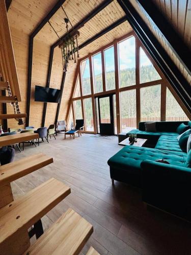 a large room with couches and tables and windows at Ascape Kabin in Broşteni