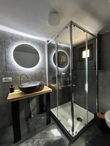 a bathroom with a glass shower and a sink at Ascape Kabin in Broşteni