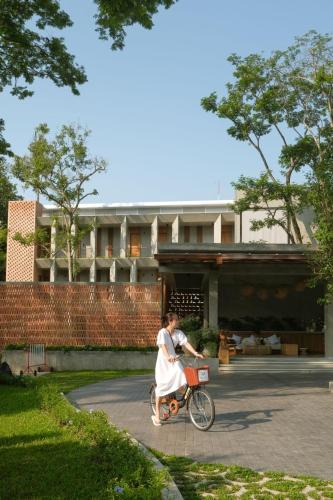 a woman riding a bike in front of a building at Proud Phu Fah Muang Chiang Mai in Chiang Mai