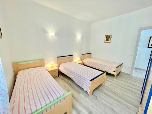 two beds in a room with white walls and wooden floors at Trilocale Jolly in Marina di Bibbona