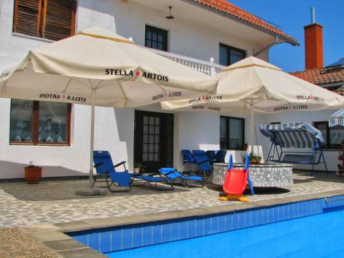 a pool with chairs and umbrellas next to a house at Vila Jovana A in Rogljevo