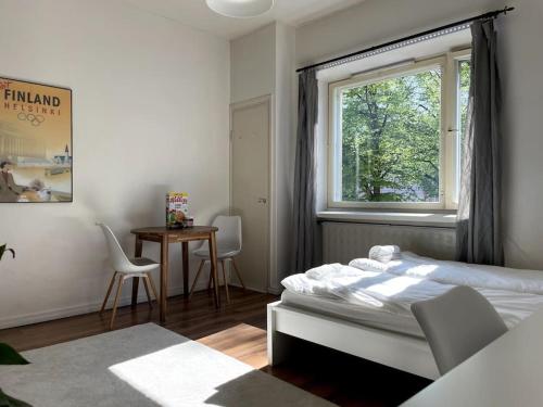 a bedroom with a bed and a window and a table at Studio The Vibe / 25min to airpt & 5min to center in Helsinki