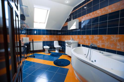 baño con azulejos azules y naranjas, bañera y aseos en Villa & SPA Owerko, en Chishki