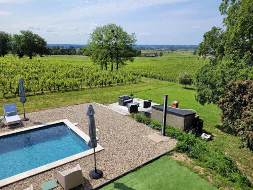 an outdoor swimming pool with a view of a vineyard at A L'OMBRE DE LA TREILLE -Proche Saint-Emilion in Saint-Magne-de-Castillon