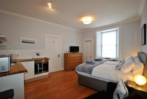 a large bedroom with a bed and a kitchen at Market Apartment- harbourfront studio Pittenweem in Pittenweem