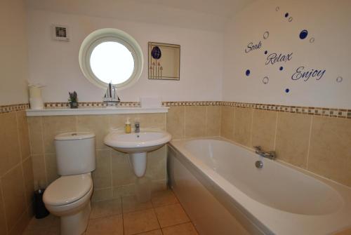 a bathroom with a toilet and a tub and a sink at Kittle View near Anstruther in Carnbee