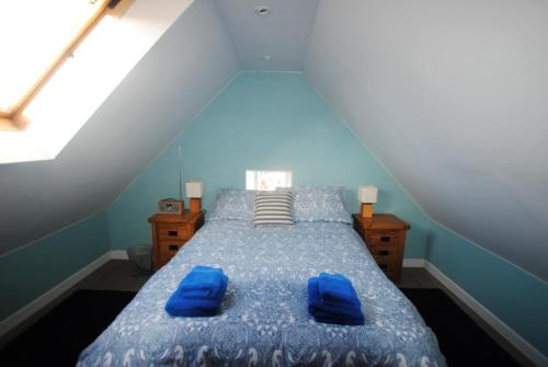 a bedroom with a bed with blue sheets and blue pillows at Harbourside- home by the sea in coastal village in Saint Monance