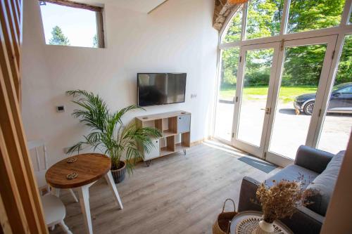 een woonkamer met een bank, een tv en een tafel bij Stunning stone coach house in Marple