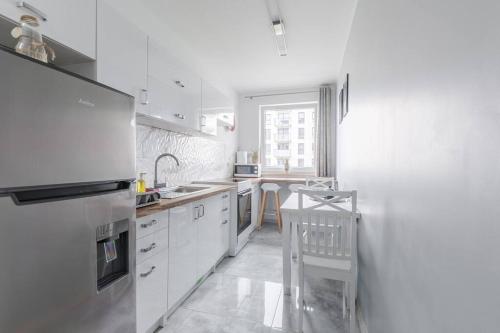 a kitchen with white cabinets and a chair in it at Central Apartments Silver L1F/21 in Gdańsk