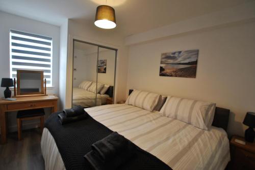 a bedroom with a bed and a desk and a television at Maeyar-contemporary apartment in coastal village in Anstruther