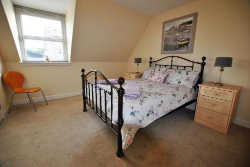 a bedroom with a bed and a chair and a window at Orchard Cottage-spacious cottage in rural setting in Kilrenny