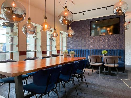 uma sala de jantar com uma grande mesa de madeira e cadeiras em Hotel De Oringer Marke & Stee by Flow em Odoorn