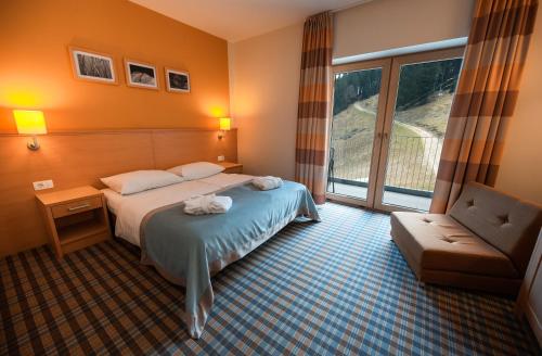 Habitación de hotel con cama, silla y ventana en Wellness Hotel Montis en Mozirje