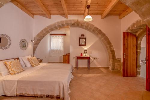 1 dormitorio con 1 cama grande y un arco en Traditional cottage near Kissamos and Falassarna 2 feel like home properties, en Áyios Vasílios