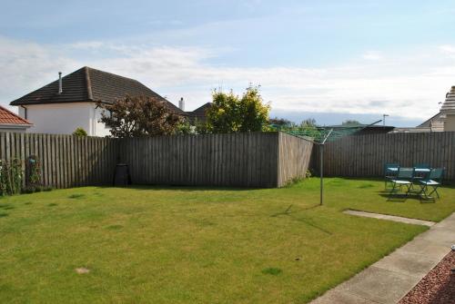 a backyard with a fence and a table and chairs at Faolin- superb detached family villa East Neuk in Anstruther