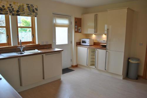a kitchen with white cabinets and a counter top at Faolin- superb detached family villa East Neuk in Anstruther