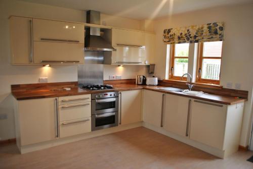 a kitchen with white cabinets and a stove top oven at Faolin- superb detached family villa East Neuk in Anstruther