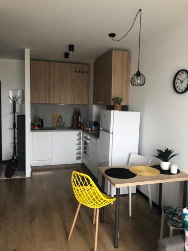 a kitchen with a table and a yellow chair at Apartament Pileckiego Nowy Dwór Mazowiecki Airport Modlin 24 H in Nowy Dwór Mazowiecki