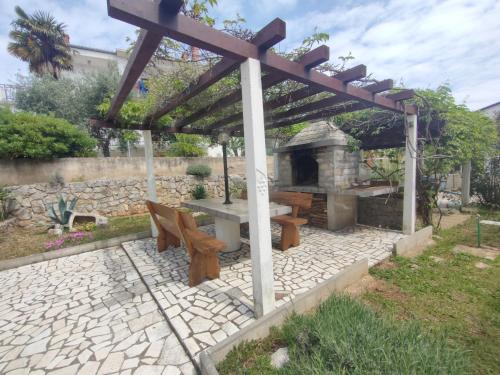 a stone patio with a picnic table and a fireplace at Apartment Alafetic in Krk
