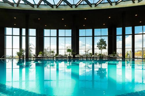 a large swimming pool in a building with windows at Kings' Valley Medical & Spa Hotel in Kazanlŭk