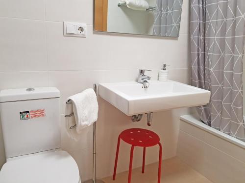 La salle de bains est pourvue d'un lavabo et d'un tabouret rouge. dans l'établissement Sunny apartment great for Cycling, 300mb wifi, à Xaló