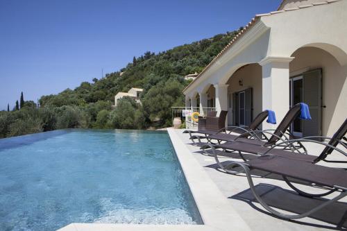 a house with a swimming pool with chairs next to it at Villa Asteri, Old Skala - Secluded Location - Panoramic Sea Views - Infinity Pool in Old Skala