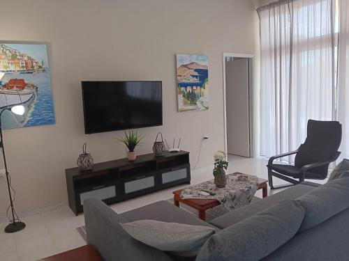 a living room with a couch and a flat screen tv at Giulias beach house in Theologos