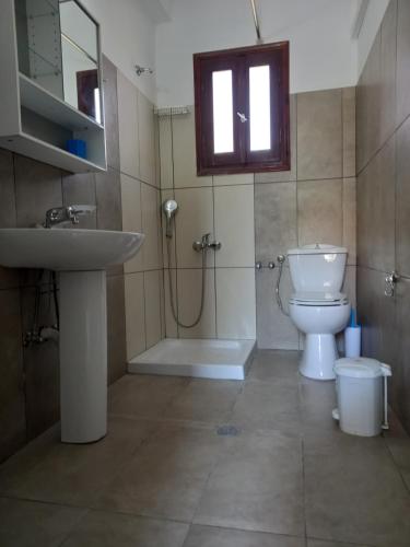 Un baño con lavabo, inodoro y ventana. en KOSTAS APARTMENTS, en Sidari