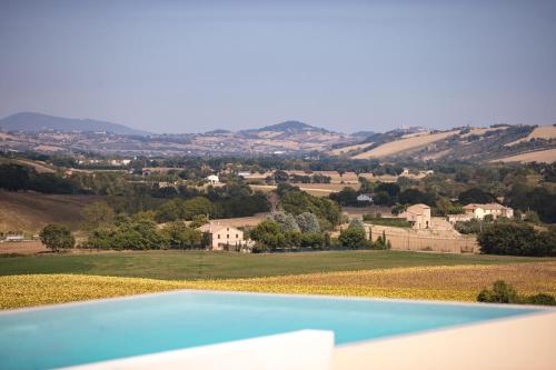 a blue swimming pool with a view of a farm at Casale Tre Gelsi in Cingoli