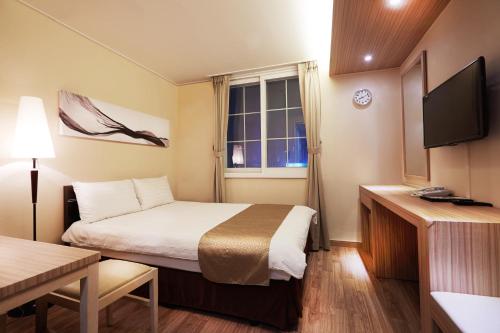 a small hotel room with a bed and a window at Uljiro Coop Residence Dongdaemun in Seoul