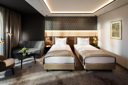 a hotel room with two beds and a chair and a couch at Kings' Valley Medical & Spa Hotel in Kazanlŭk