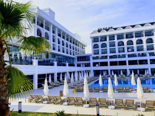un hotel con sillas y sombrillas frente a un edificio en Sunthalia Hotels & Resorts Ultra All Inclusive Adults Only Party Hotel en Side