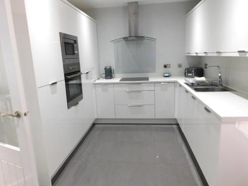 una cocina blanca con armarios blancos y fregadero en Beautiful 3 bedroom home with large garden 35 mins to Glasgow & Edinburgh en Whitburn