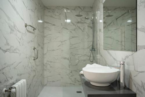 Baño blanco con lavabo y espejo en Hotel Montañés, en Suances