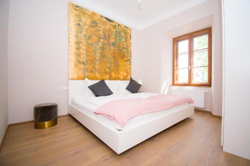 1 dormitorio con 1 cama blanca y una pintura en la pared en Das Torhaus en Feldbach