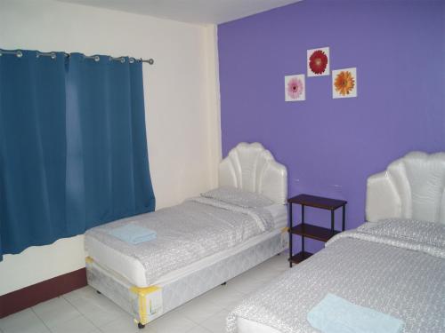 two beds in a room with purple walls at Pineapple Guesthouse in Karon Beach