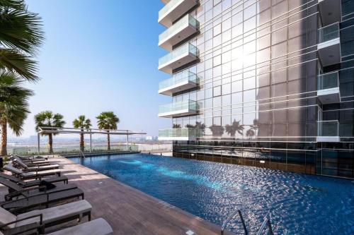 an exterior view of a building with a swimming pool at Tranquil Studio in Damac Hills in Dubai