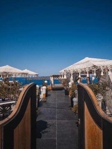 a walkway with umbrellas on the beach at Galaxy Suites & Villas in Imerovigli