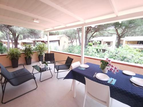 eine Terrasse mit einem Tisch, Stühlen und Pflanzen in der Unterkunft Appartamento due passi dal mare in Fort Village