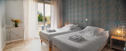 a hotel room with two beds and a window at Hôtel Restaurant La Voile Bleue in Erdeven