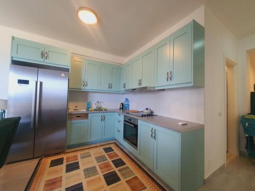 een keuken met blauwe kasten en een roestvrijstalen koelkast bij White SideSea View Apartment in Sarandë