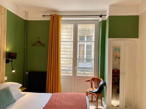 - une chambre avec des murs verts, un lit et une fenêtre dans l'établissement Hôtel Madame, à Bordeaux