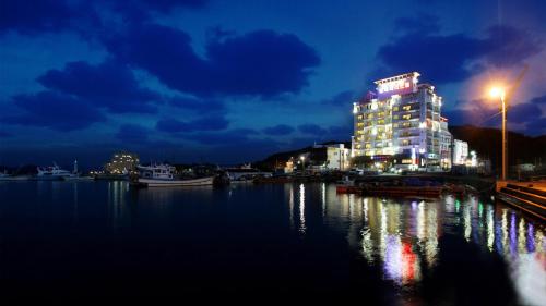 a lit up building on the water at night at Tongyeong Bay Condo Hotel in Tongyeong